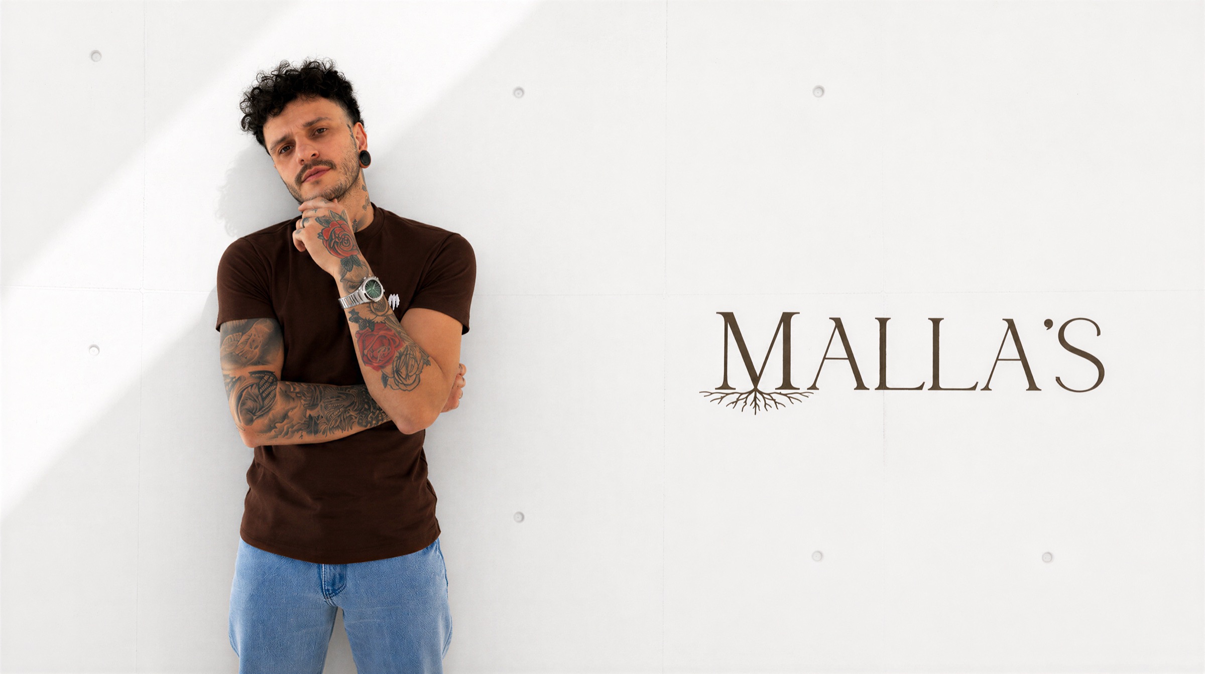Mallas atendendo um cliente na barbearia, ambiente sofisticado e acolhedor